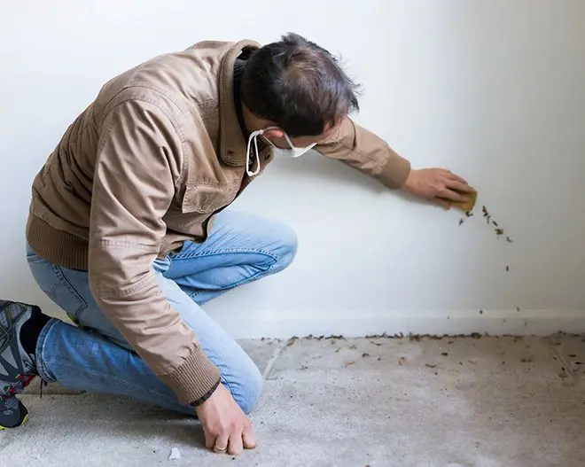 A man sitting on the ground in front of a wall.