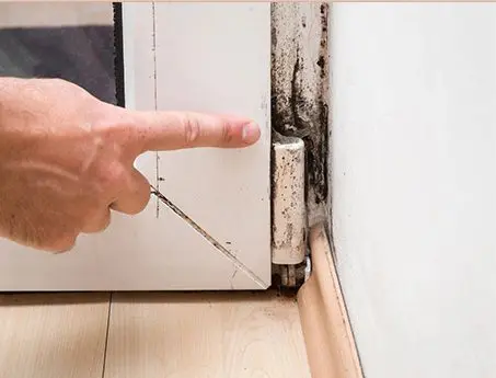 A person points to the wall of an old kitchen.