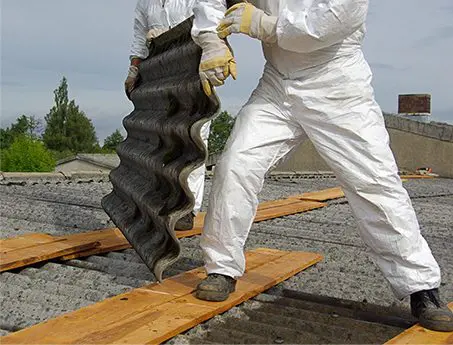 A man in white suit holding an object on top of railroad tracks.