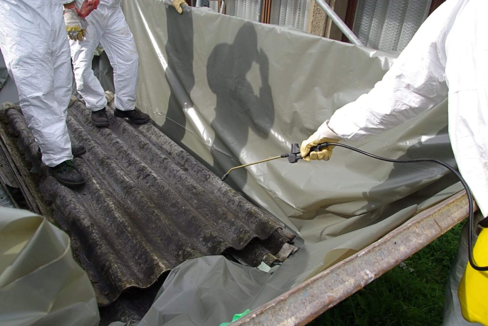 A man spraying paint on the back of a truck.